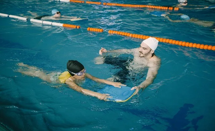 5 Engaging Activities to Unleash the Aquatic Potential of Your Kids coach teaching kid indoor swimming pool how swim dive swimming lesson kids development