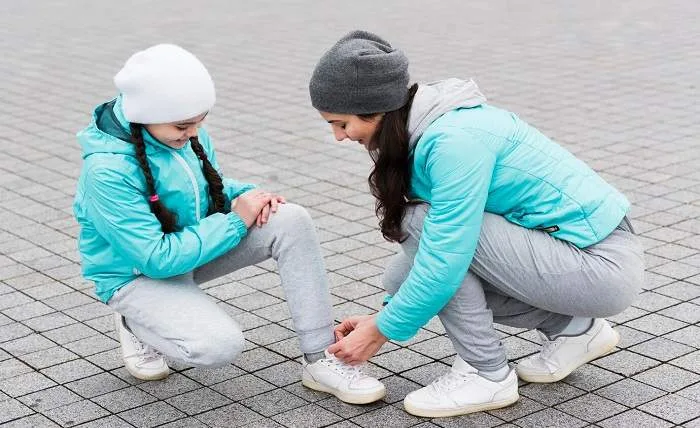 What To Do If You Sprain Your Ankle mom tying shoe laces daughter 23 2148503222