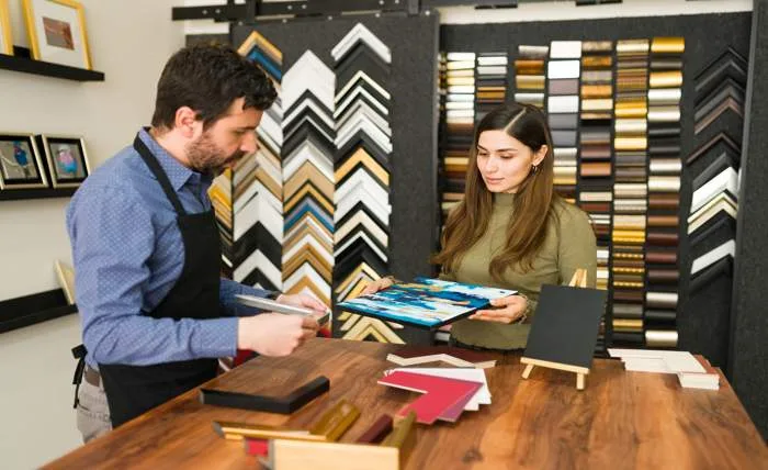 How to choose wallpaper for a wall young female client frame store is showing male employee her painting because she is looking buy new frame